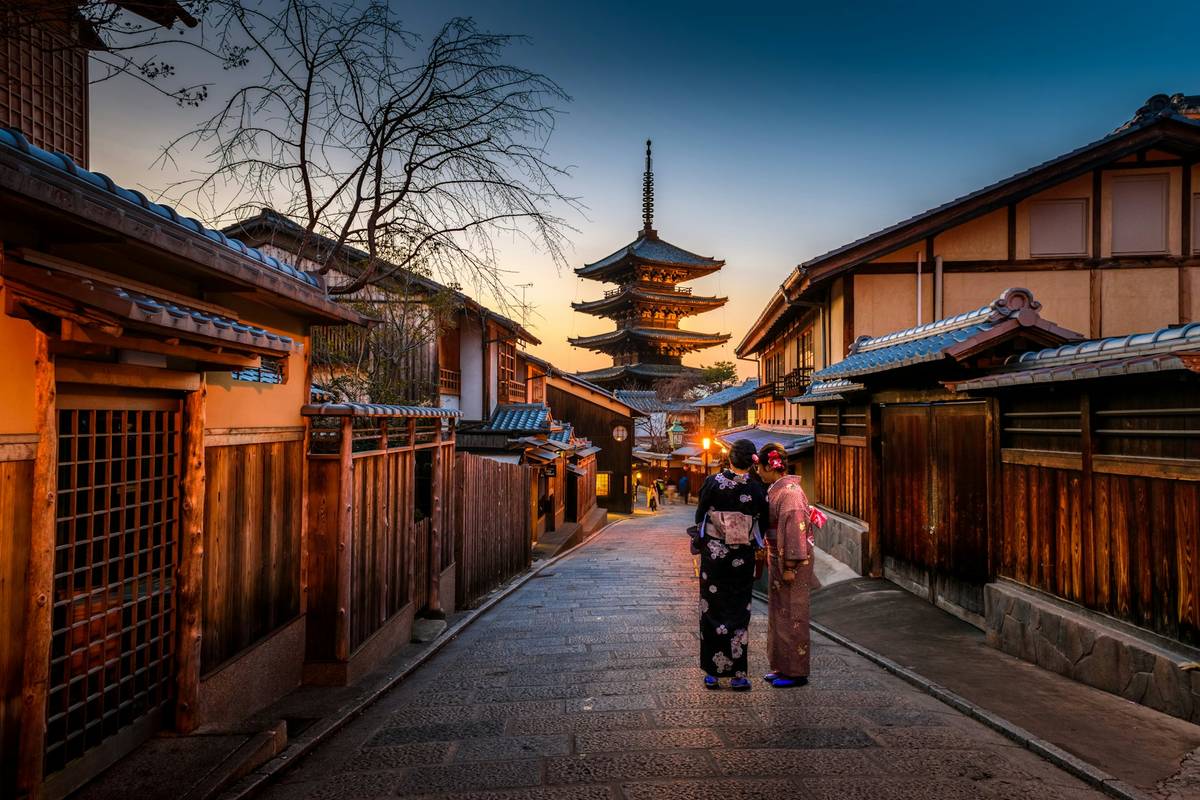 Lantern lit street leading to a pagoda in Kyoto at dusk
